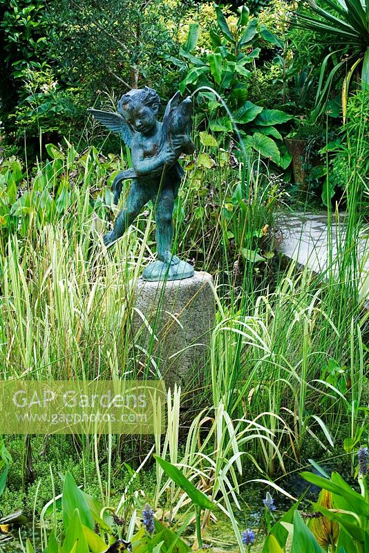 A water feature statue in the Italian Garden with pond and grasses - The Lost Gardens of Heligan in Cornwall