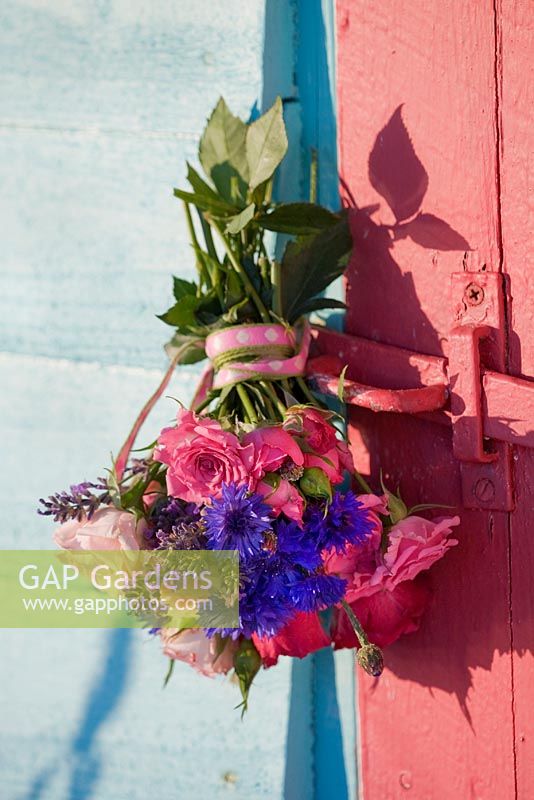 Roses, lavender and cornflower bouquet, hanging on an old door