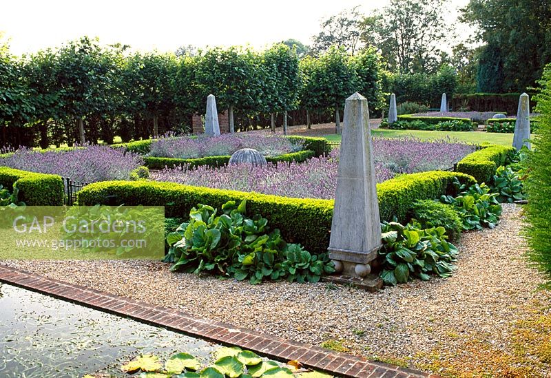 Formal geometric garden with stone obelisks and balls, planted with Lavandula, Buxus and Bergenia 