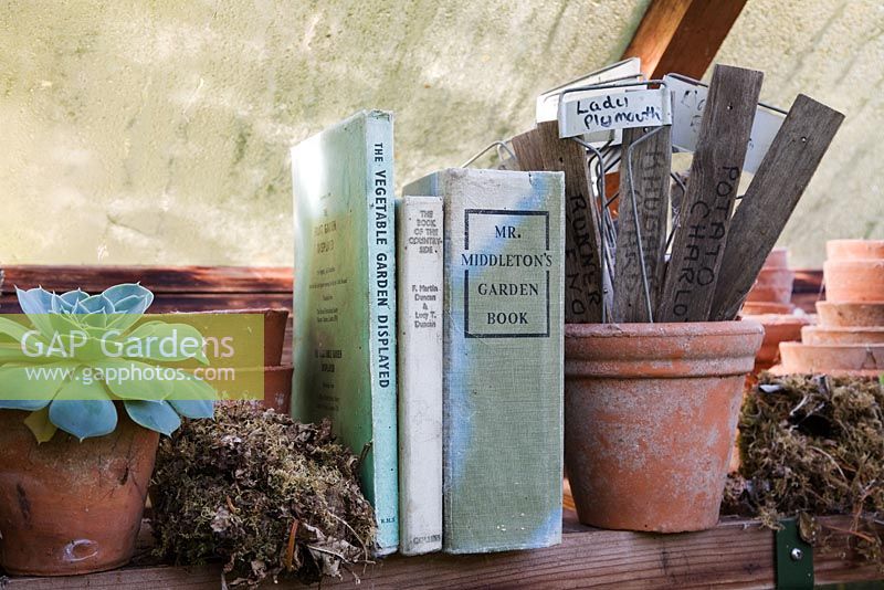 Collection of old gardening books, plant labels, and birds nests in the greenhouse