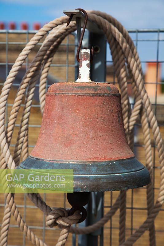Old ships bell with rope hanging from galvanised mesh fence - Roof Terrace Garden 
