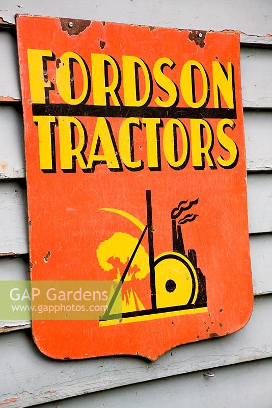 Old sign on the shed in a quirky town garden in May filled with antique objects and Alliums.