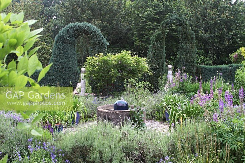 Conifer arches planted with borders of Delphiniums, Geraniums and Baptisia - The Life-gardens of Groot Hontschoten, western gardens in accordance with the Zen principle.