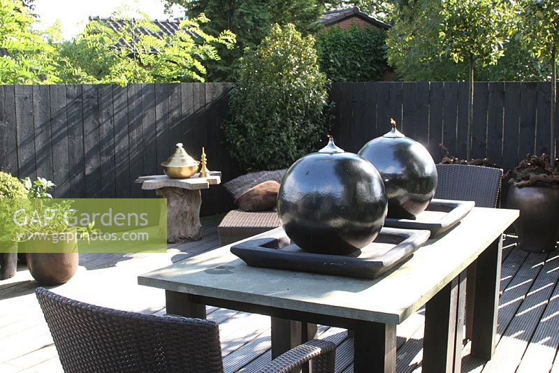 Large spherical oil burners on table on roof terrace in summer.