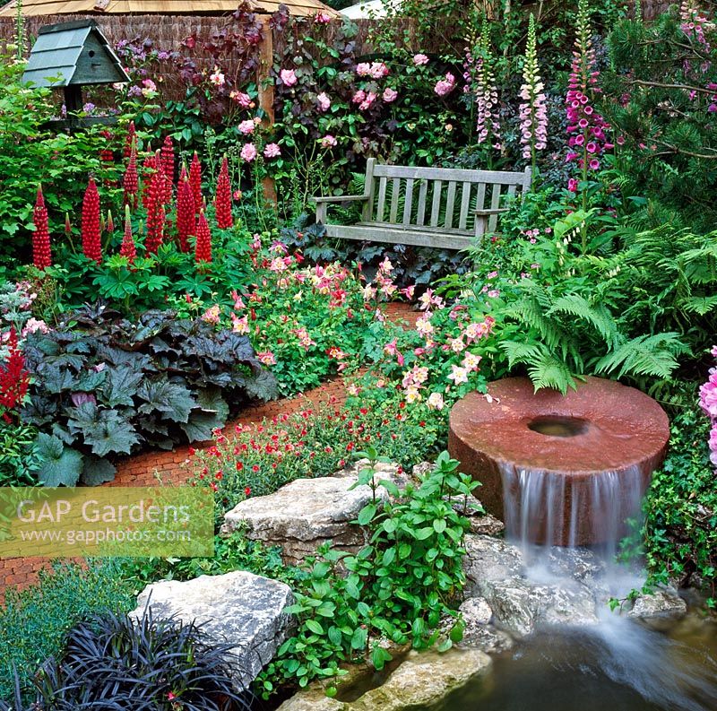 Millstone waterfall in Cottage garden setting with seat in background. Daily Telegraph Garden, Chelsea Flower Show, 1994 