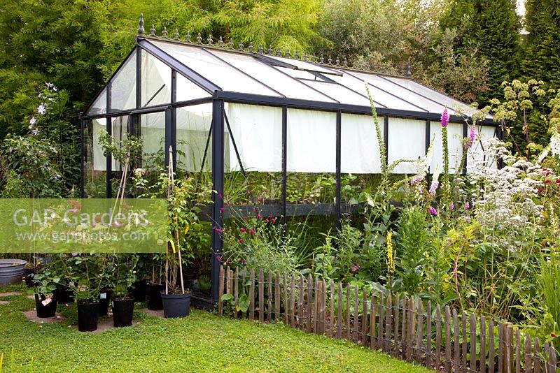 Greenhouse in summer garden with shades over windows.