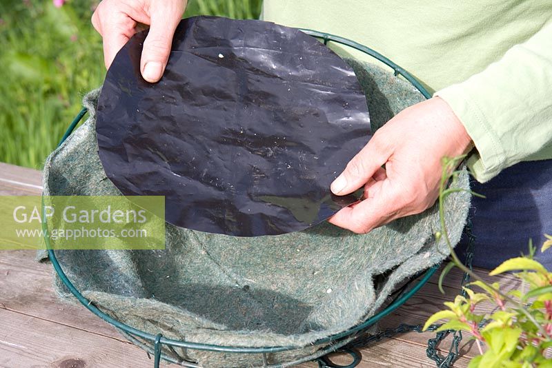 Planting up a hanging basket - adding a plastic disc to the fibre liner