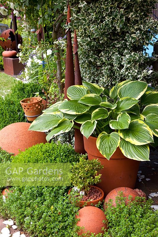 Border with Hosta in pot and clay ornaments 