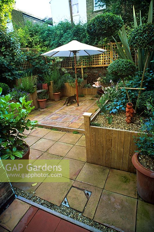 Raised beds, pot plants, paved patio, parasol and trellis in urban garden - After a makeover of a Brixton garden for Channel 4 Garden Doctors