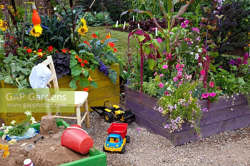 Children's garden with sandpit and vegetables growing in raised bed