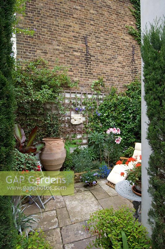 Small urban courtyard garden in London with yorkstone paving