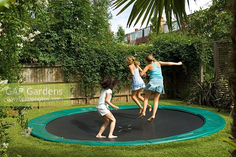 Children jumping on trampoline in urban garden. Barnes London