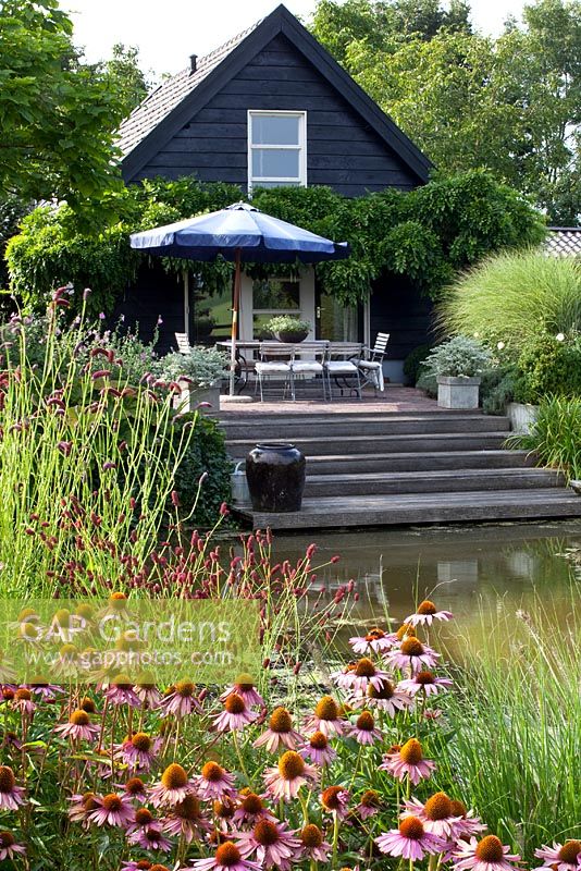 Seating area overlooking pond with perennial planting of Echinacea purpurea and Sanguisorba 