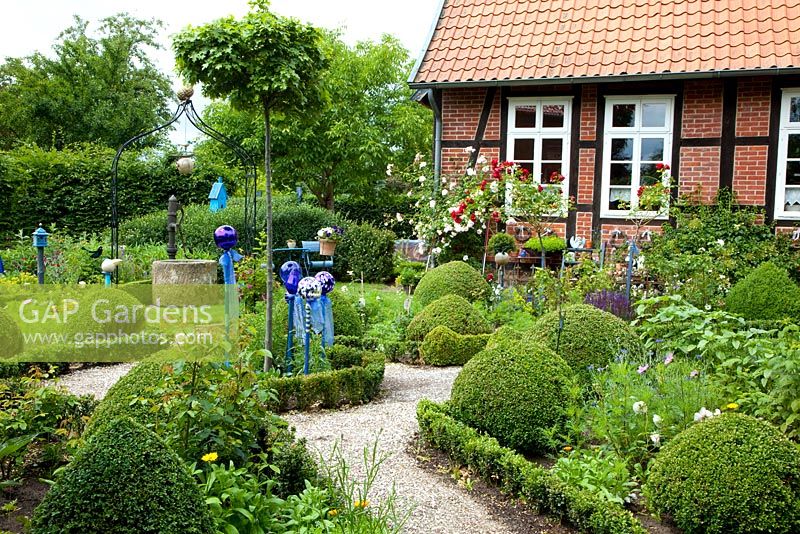Cottage garden with clipped box, gravel paths and glass ornaments 