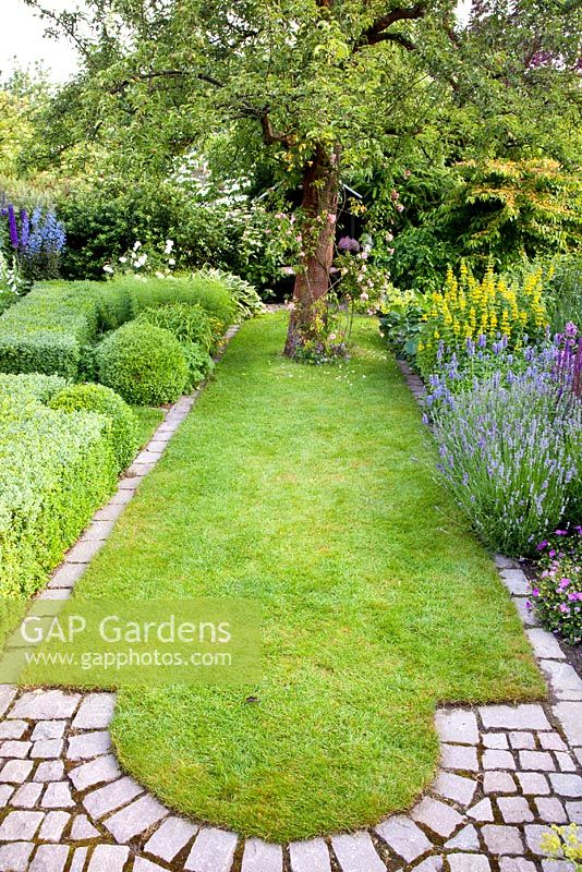 Small formal lawn in country garden with a granite sett edging