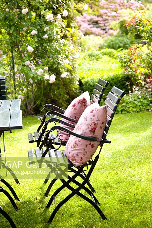 Metal chairs on lawn in country garden