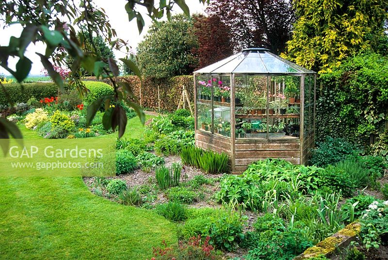 Octagonal cedarwood greenhouse and informal herbaceous beds in spring