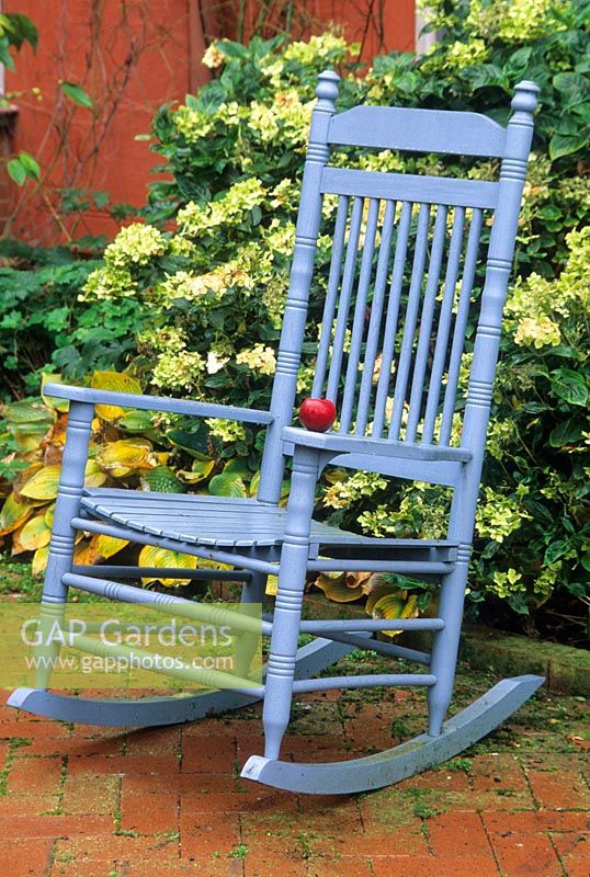 Blue rocking chair with red apple on terrace