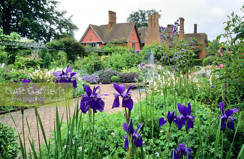 The main garden in summer with pool and fountain. Iris sibirica in foreground