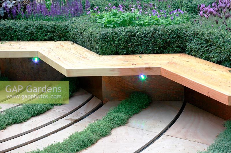 Thyme growing through contemporary paving near wooden bench - Global Stone Bee Friendly Plants Garden, Silver medal winner at RHS Chelsea Flower Show 2010
