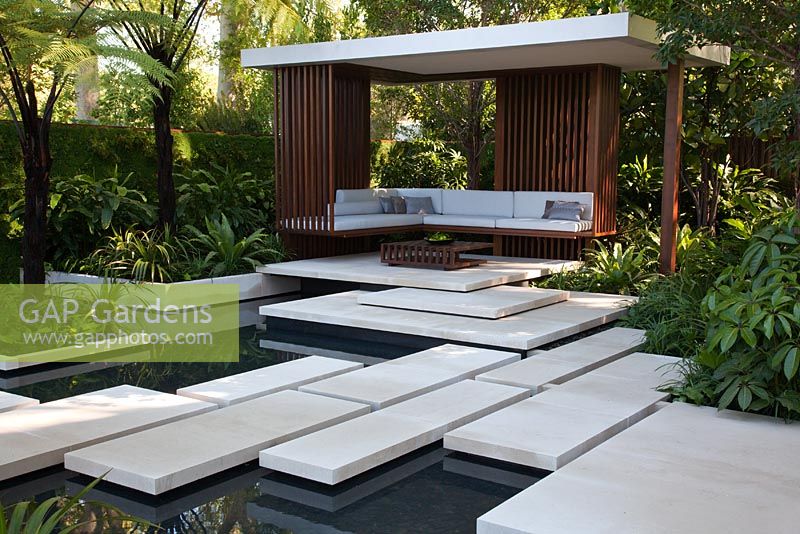 Large paved stepping stones cross water towards a pavilion bordered by lush tropical planting and tree ferns Cyathea latebrosa - The Tourism Malaysia Garden, Gold medal winner, RHS Chelsea Flower Show 2010 
