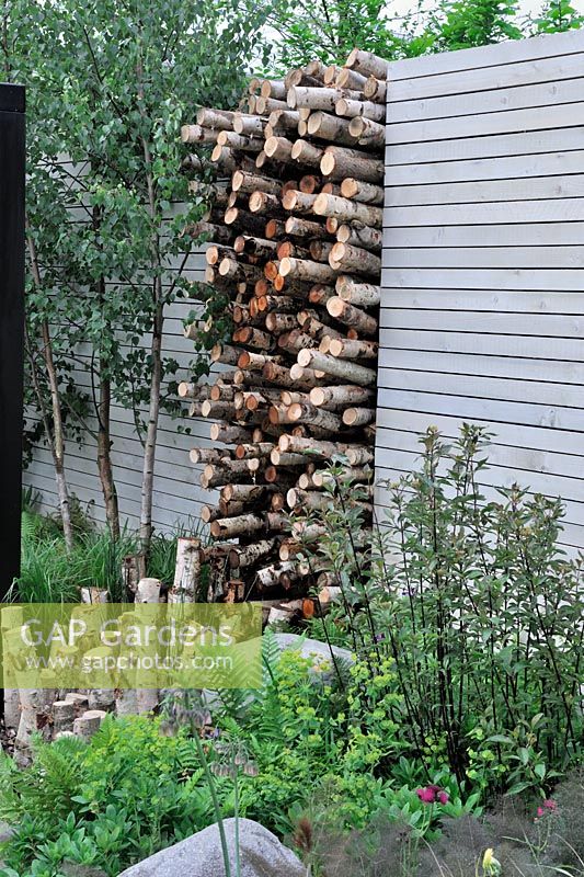 Stack of Betula stumps in wall space. The Naturally Fashionable Garden, Silver Medal winner, RHS Chelsea Flower Show 2010
