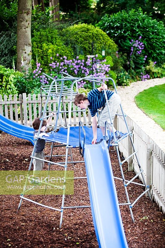 Oliver and Rueben (grandchildren of owner) on climbing frame in play area in back garden. Mathern House, Mathern, Monmouthshire, Wales. Early June. Garden opens for National Gardens Scheme.
 