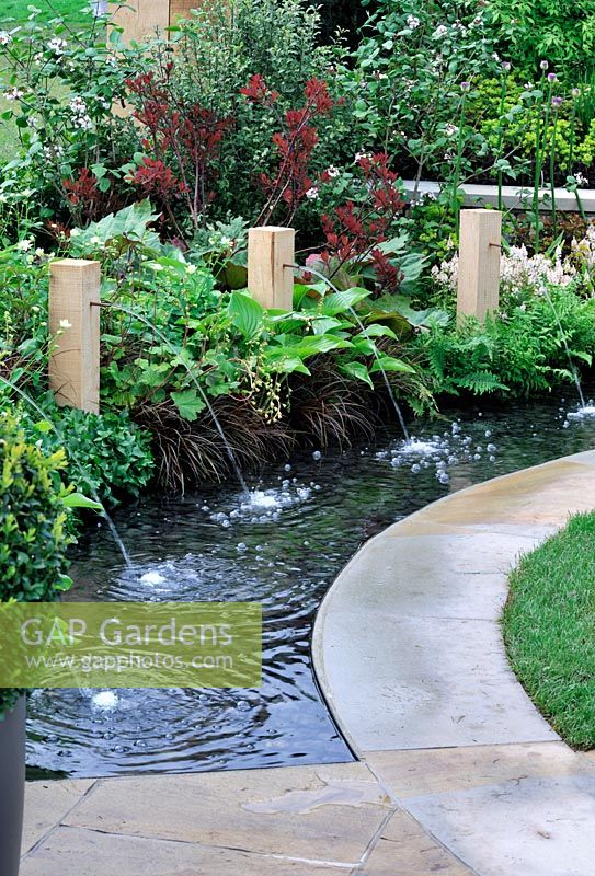 Circular rill with copper water spouts fixed in timber pillars - RHS Malvern Spring Gardening Show