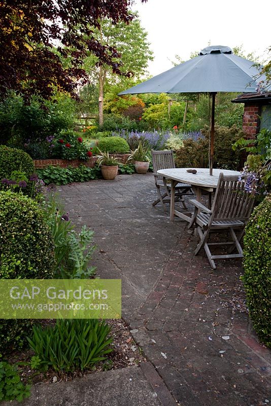Garden furniture surrounded by extensive early summer planting - Old Buckhurst, 