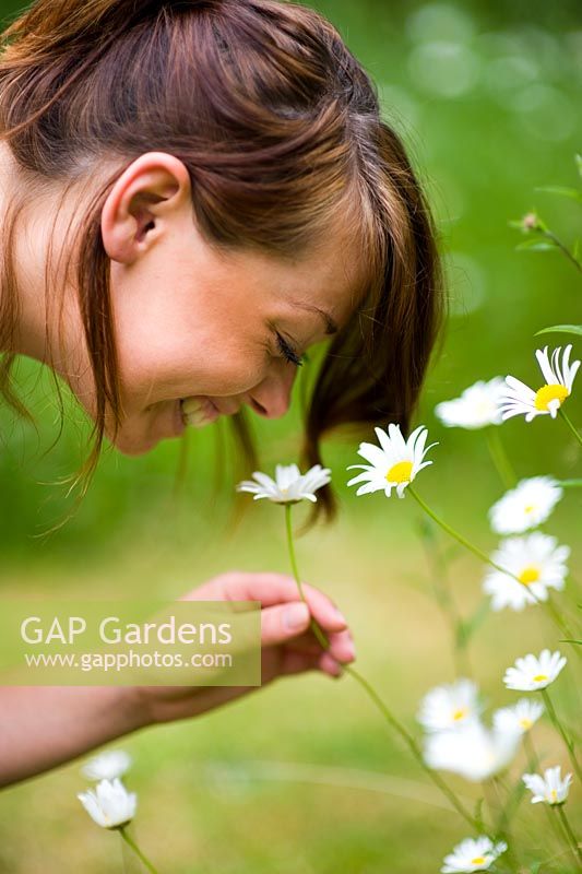 Woman smelling daisies in the garden