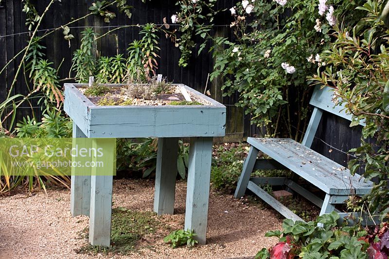 Wooden table planted with herbs and bench in the Herb Garden, Barnsdale Garden
