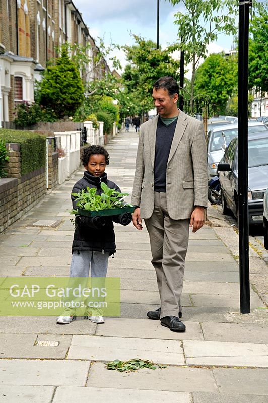 Little boy with his father carrying a tray of plants in an urban street in Hackney, London