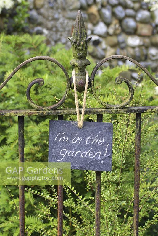 Slate sign on wrought iron gate, reading 'I'm in the garden'