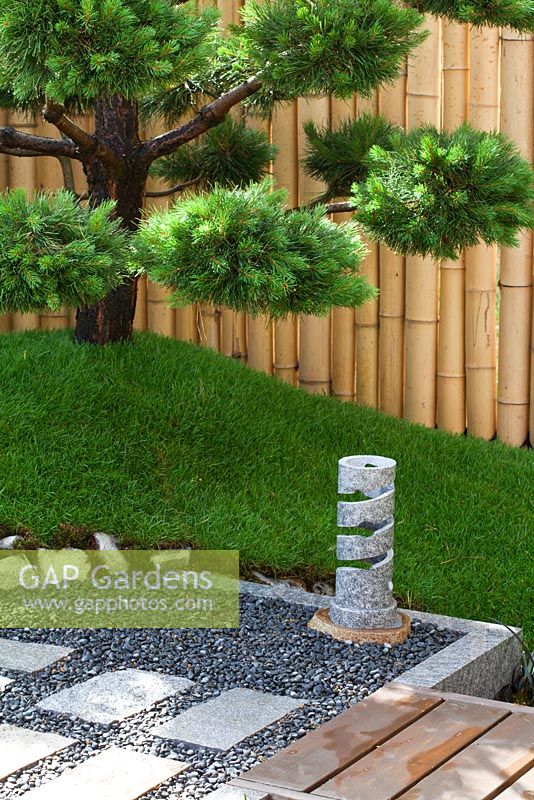 Gravel, stone patio and Pine tree with bamboo fence behind. 'Konpira-san' - Gold Medal Winner - RHS Hampton Court Flower Show 2010 