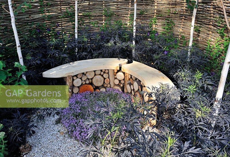 Curved stone and timber bench surrounded by Willow fencing. 'It's Only Natural' - Silver Gilt Medal Winner - RHS Hampton Court Flower Show 2010 
 