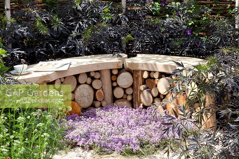 Curved stone and timber bench surrounded by Sambucus nigra 'Black Lace' and Thymus - Thyme. 'It's Only Natural' - Silver Gilt Medal Winner - RHS Hampton Court Flower Show 2010 
 
