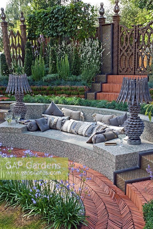 Tiled outdoor seating area with wooden lamps surrounded by a herringbone path, plants include Agapanthus 'Blue Cloud', Lavandula angustifolia 'Alba', Koeleria glauca and Armeria maritima 'Alba'. 'The Garden Lounge' - Silver Gilt Medal Winner - RHS Hampton Court Flower Show 2010 
 