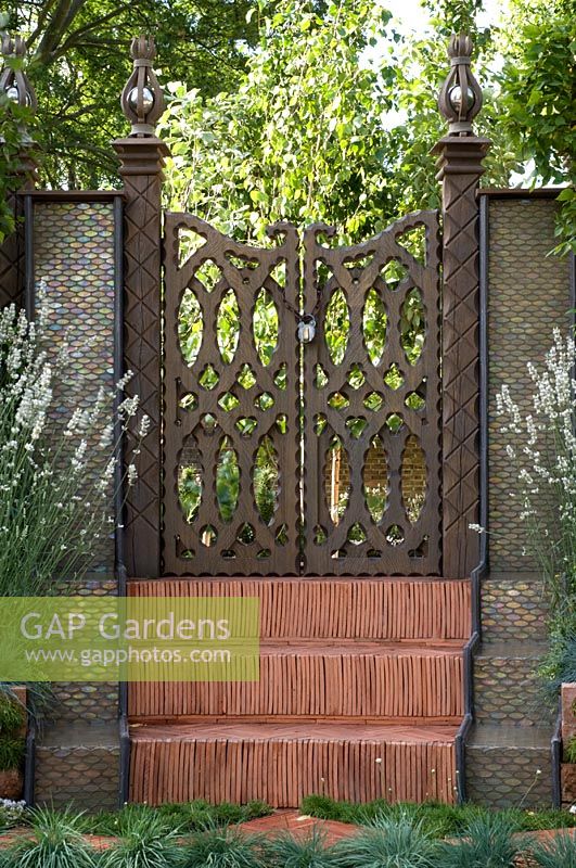 Herringbone tile steps leading to a carved wooden gate, with rainbow effect water feature and Lavandula angustifolia 'Alba'. 'The Garden Lounge' - Silver Gilt Medal Winner - RHS Hampton Court Flower Show 2010 
 
