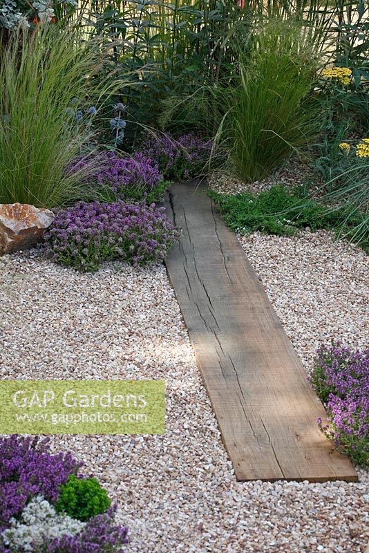 Herbs, grasses, gravel and wooden path in 'The Fire Pit Garden' - Silver Medal Winner at the RHS Hampton Court Flower Show 2010