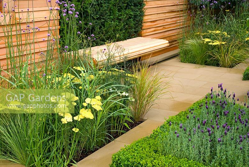 Wooden bench and symmetrical mixed beds with perennials including Verbena and Achillea, Buxus topiary and Lavandula in the Christie 'Embracing Tranquility' garden - RHS Tatton Flower Show 2010