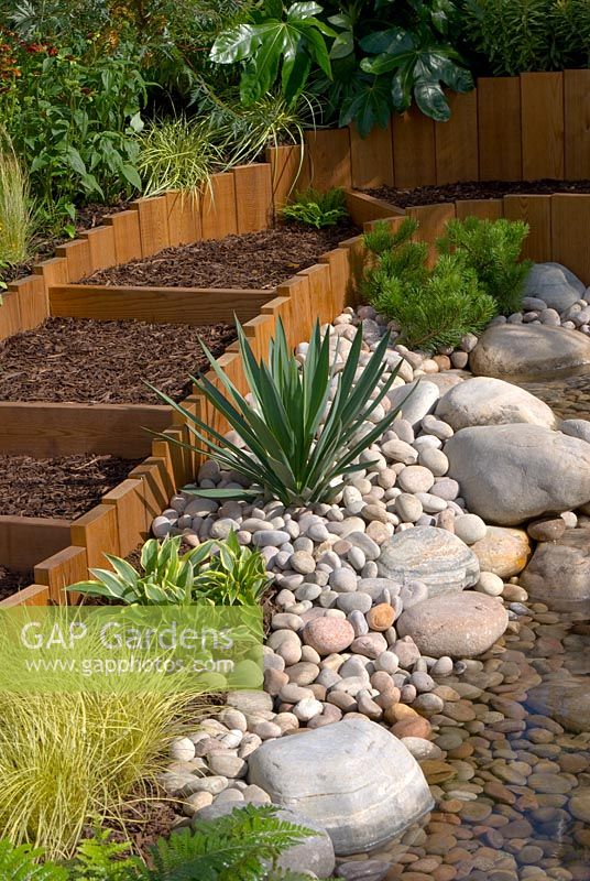 Wooden and bark chipping steps with adjacent planted pebble bed and stream. Southport Flower Show 2010