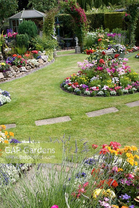 Colourful back garden with borders filled with tender bedding plants, including Alyssum, Begonia, Geranium, Impatiens, Lobelia and Marigold, herbaceous border and summer house. Manvers Street, Derbyshire NGS
