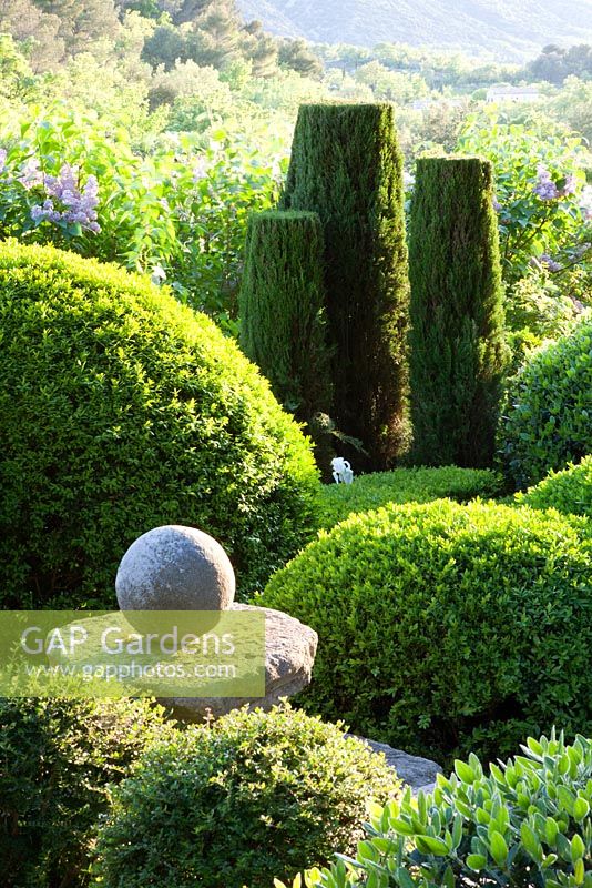 Topiary and stone finial in La Louve garden, Provence, France