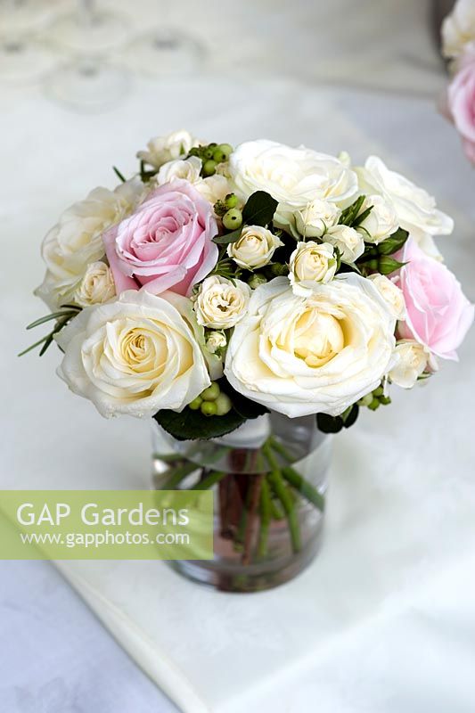 Bouquet of cream and pink roses in a glass vase on a table with linen tablecloth