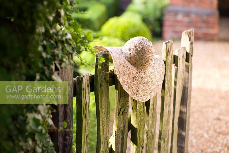 Straw sun hat placed on a rustic wooden garden gate
