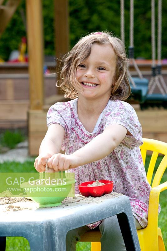 Girl playing with sand in garden