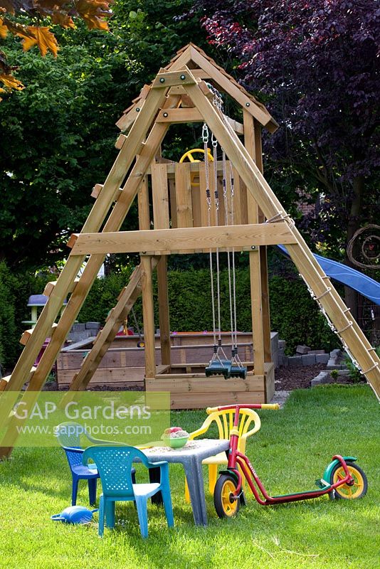 Childrens play area with wooden climbing frame and swings