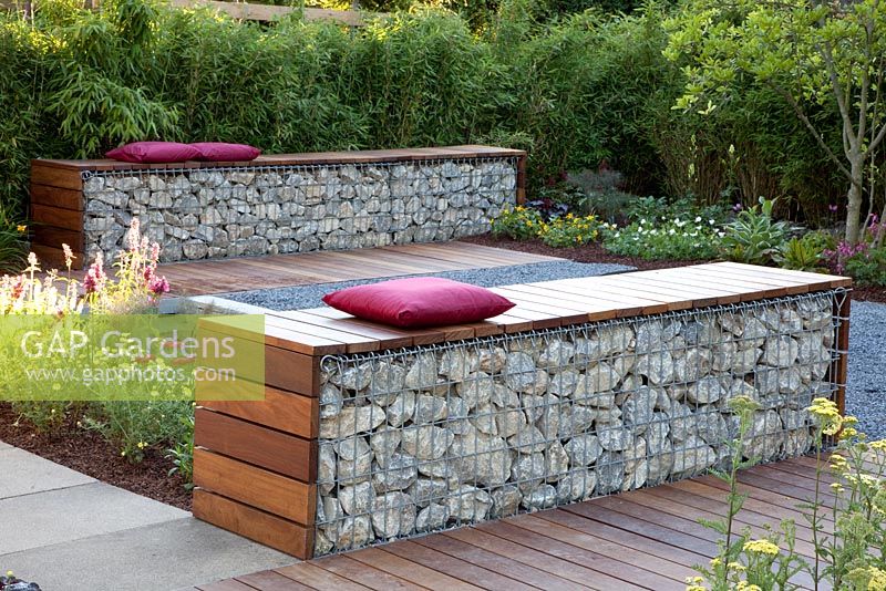 Small garden with patio and benches made from wood and gabions backed by Fargesia murielae - Bamboo hedge
 