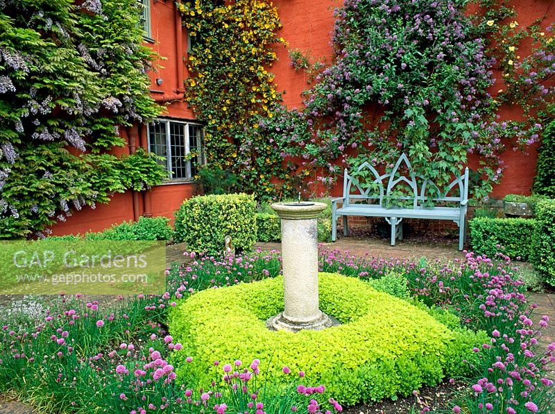 The herb garden with sundial underplanted with Origanum vulgare 'Aureum' and Chives at Wyken Hall, Suffolk