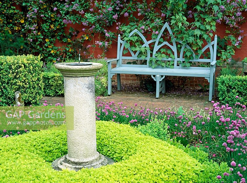 The herb garden with sundial underplanted with Origanum vulgare 'Aureum' and Chives at Wyken Hall, Suffolk